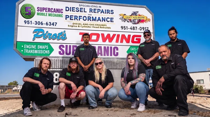 The Supercanic crew in front of the shop sign